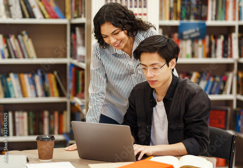 Latin counselor standing and looking at student's work