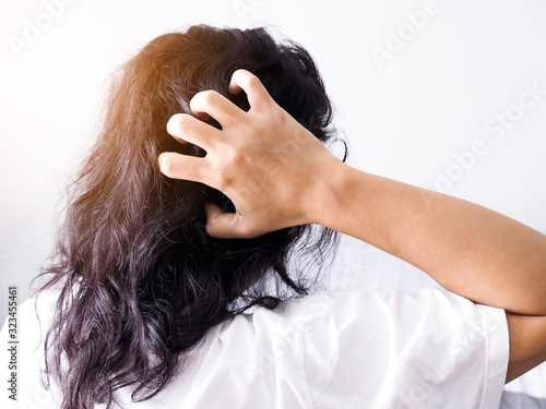 Asian women with dark hair with itchy head and use hand scratching and messy hair. Hair health problems.