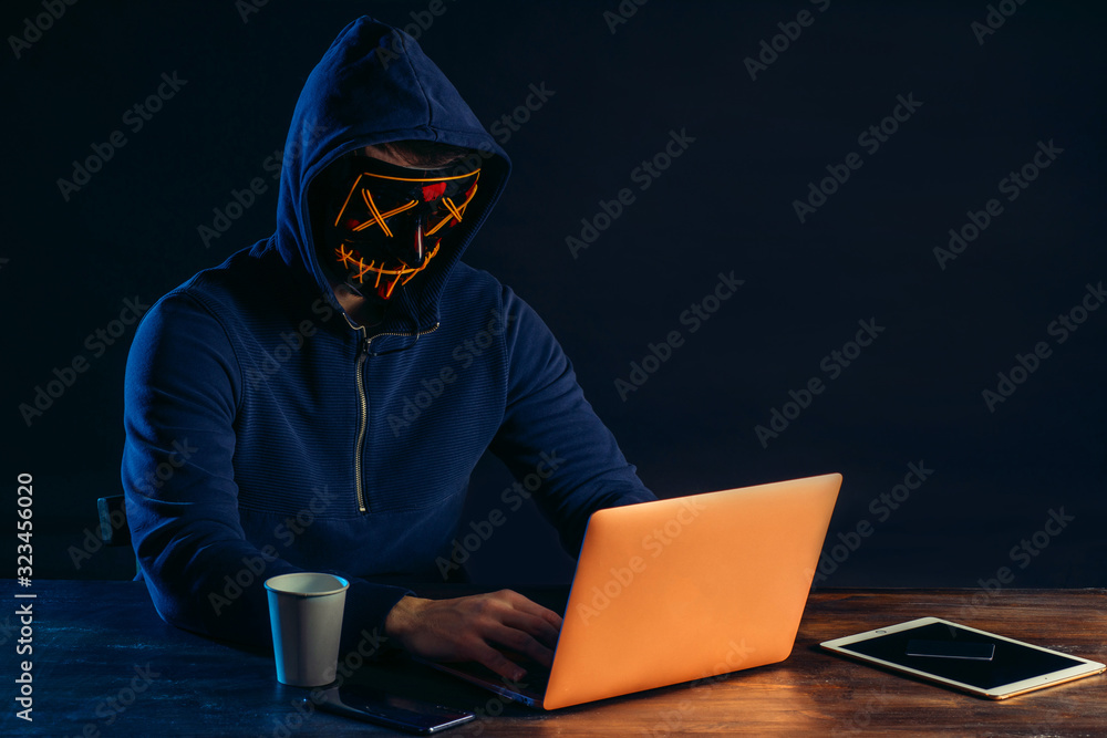 young dangerous hacker bandit engaged in crime, don't afraid of strangers, entered the room and hack laptop system, password. cyberattack nowadays. isolated in dark space young dangerous hacker bandit engaged in crime, don't afraid of strangers, entered the room and hack laptop system, password. cyberattack nowadays. isolated in dark space