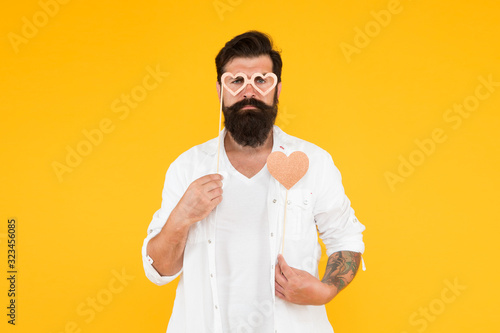 serious male hipster in party glasses. bearded man hipster yellow background. love heart for valentines day holiday. happy birthday. brutal man with beard fall in love. romantic date © be free