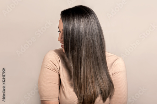 Beautiful plus size model with long colored glossy hair posing on beige studio background