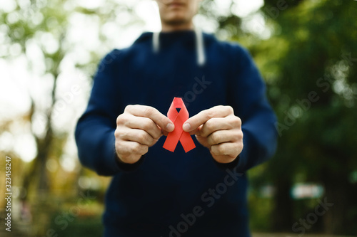 red aids ribbon in hand on green background, HIV photo