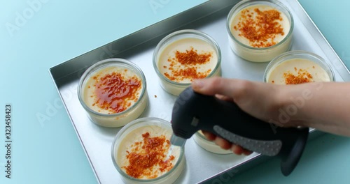 Caramelizing sugar on the top of creme brulee dessert using gas torch