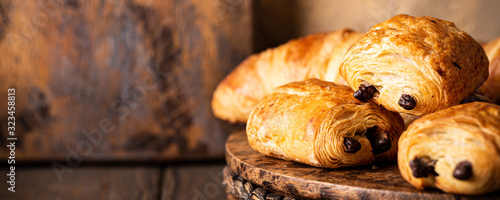 Photo Freshly baked sweet buns puff pastry with chocolate and croissants on old wooden background