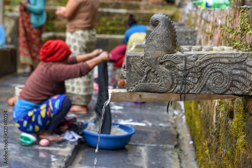 Women washing clothes at the fountain of Bandipur village on Nepal photo