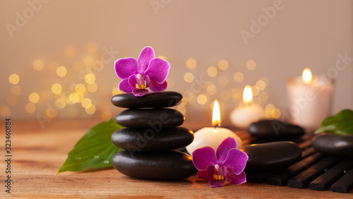 Massage stone, orchid flowers and burning candles. Spa and beauty background.