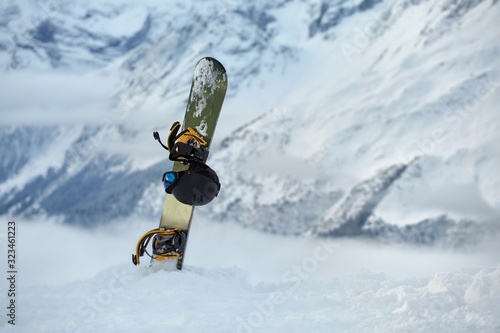 Snowboard and helmet in the snow above the snowy slopes