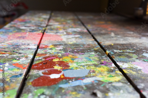 Artists workshop or studio bench covered with splattered paint built up in authentic texture on painted surface