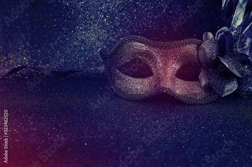 Photo of elegant and delicate black Venetian mask over dark glitter background © tomertu