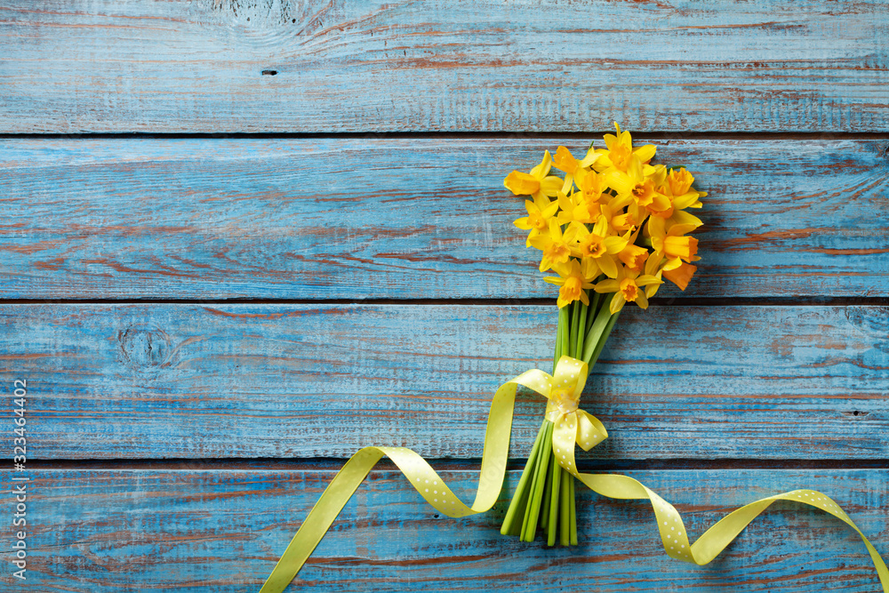 Spring daffodil flowers on blue rustic background. Beautiful bouquet for Women day, Mother day. Top view. - obrazy, fototapety, plakaty 