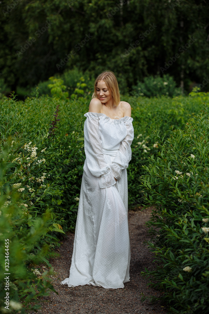 blonde in white dress posing in green blonde in white dress posing in green