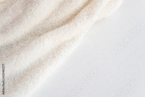 Soft cozy plush fabric with pile lies in beautiful folds on white marble countertop background. Copy space.