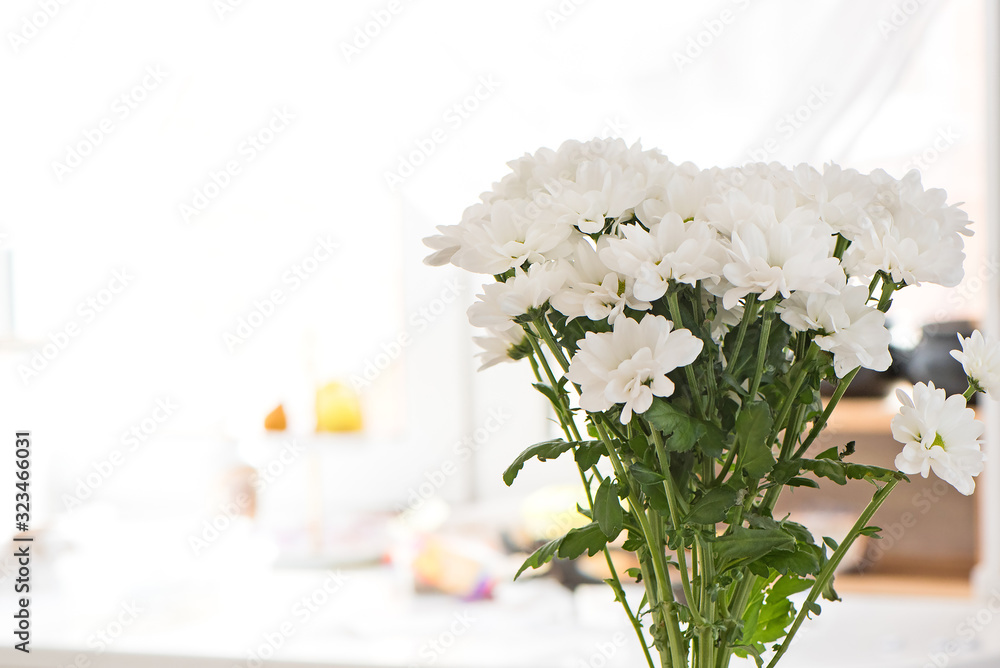 Bouquet of white chrysanthemums close-up on blurred background inside the home environment. Copy space