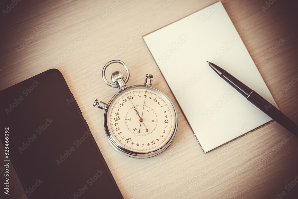 Smartphone, Notepad, pen And Stopwatch biege desk table background. The concept of time management Smartphone, Notepad, pen And Stopwatch biege desk table background. The concept of time management