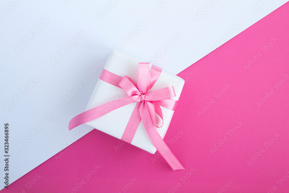Gift with pink  bow in the center of the two-color background. Top view. Copy space.