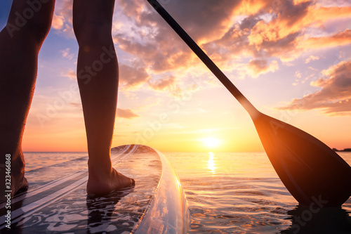 Obraz na plátně Stand up paddle boarding or standup paddleboarding on quiet sea at sunset with b