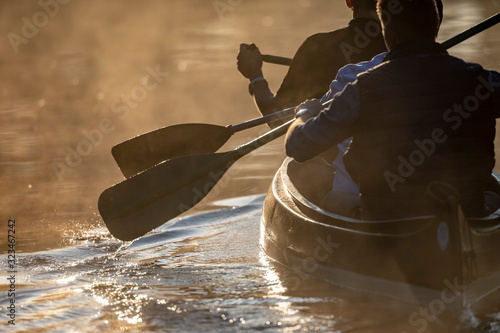 Ruderblatt taucht in der Morgendämmerung bei gegenlicht auf einem Flussin s Wasser ein photo