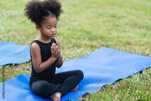 Fotografie, Obraz African american little girl sitting on the roll mat practicing meditate yoga in