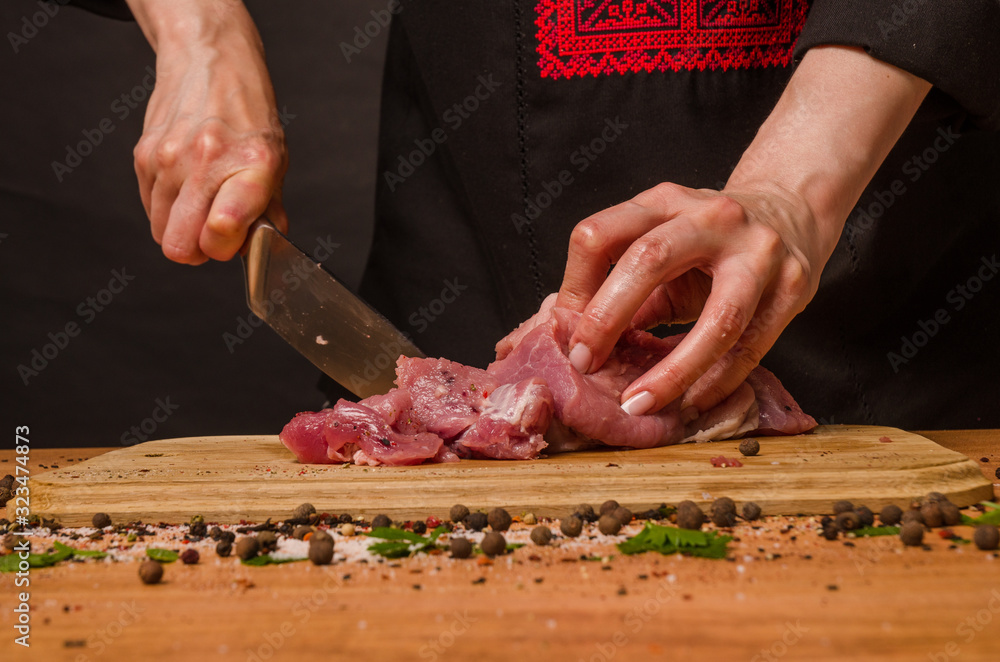 Female hands with a knife in their hand cut fresh meat on a table