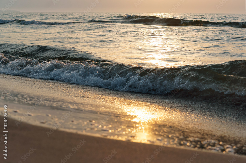 Sunset over the sea. Reflection of sunlight in the sea waves. The sky in the sunset rays.