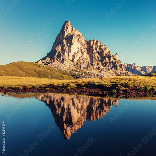 Scenery of nature with sunlight. Great view of Giau Pass, Italian Dolomites, with the peaks of teh mountain and perfect sky reflected in a small lake, popular travel and hiking destination.