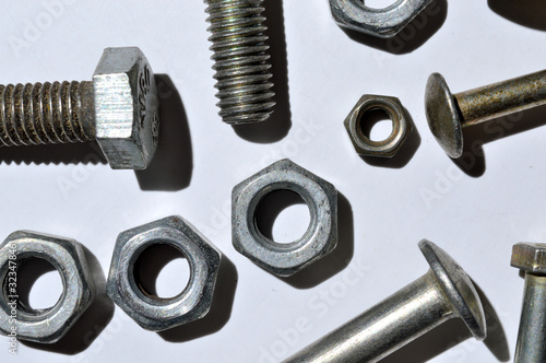 bolts and nuts of different sizes lie on a white background. top view.