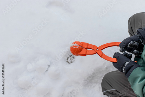 child in ski gloves holds a device for making snowballs. winter outdoor entertainment. copy space