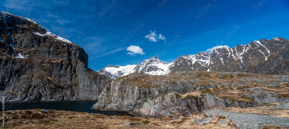 Panorama of picturesque landscape scenery with snow covered mountains and blue sky. From Aa in Lofoten, Norway.