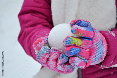 Hands with mitten holding a snow ball