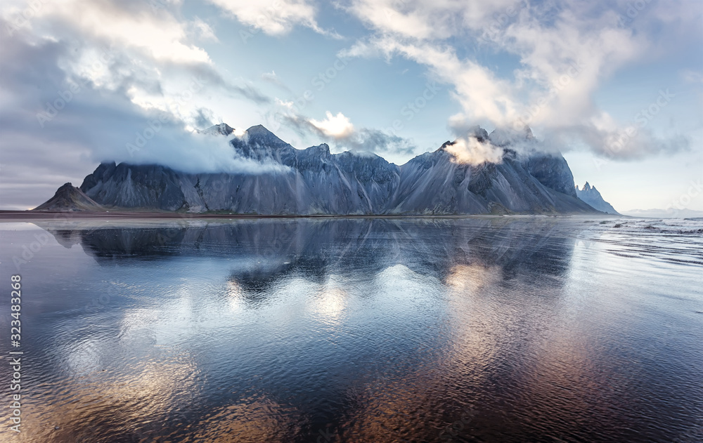 Wonderful nature landscape. Impressive view on Famous Vestrahorn Mountain in clouds with reflection. Popular travel location. Stokksnes cape the most famous place of Iceland. Beauty in the world