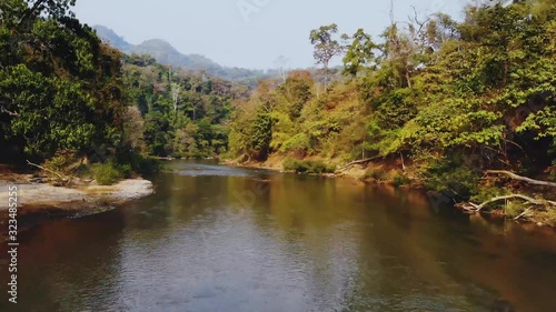 Aerial tracking view over the river surface between the trees, of thailand