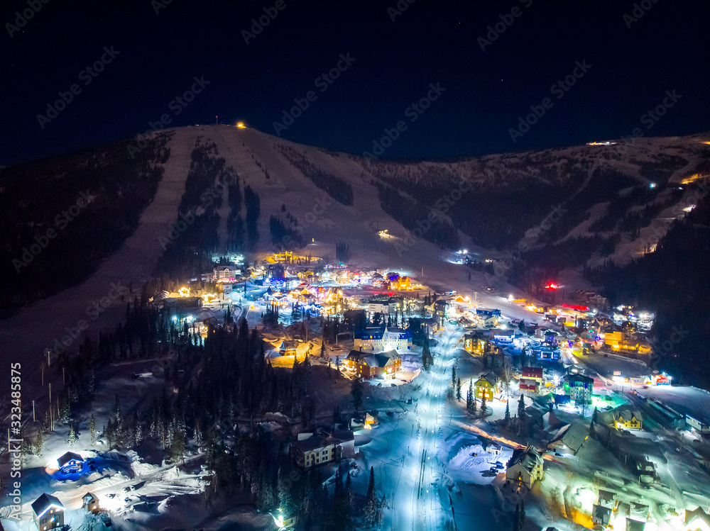 Fototapeta premium Sheregesh Kemerovo region ski resort in winter, night landscape on mountain and hotels, aerial view