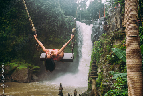 Beautiful girl having fun at the waterfalls in Bali. Concept about wanderlust traveling and wilderness culture photo