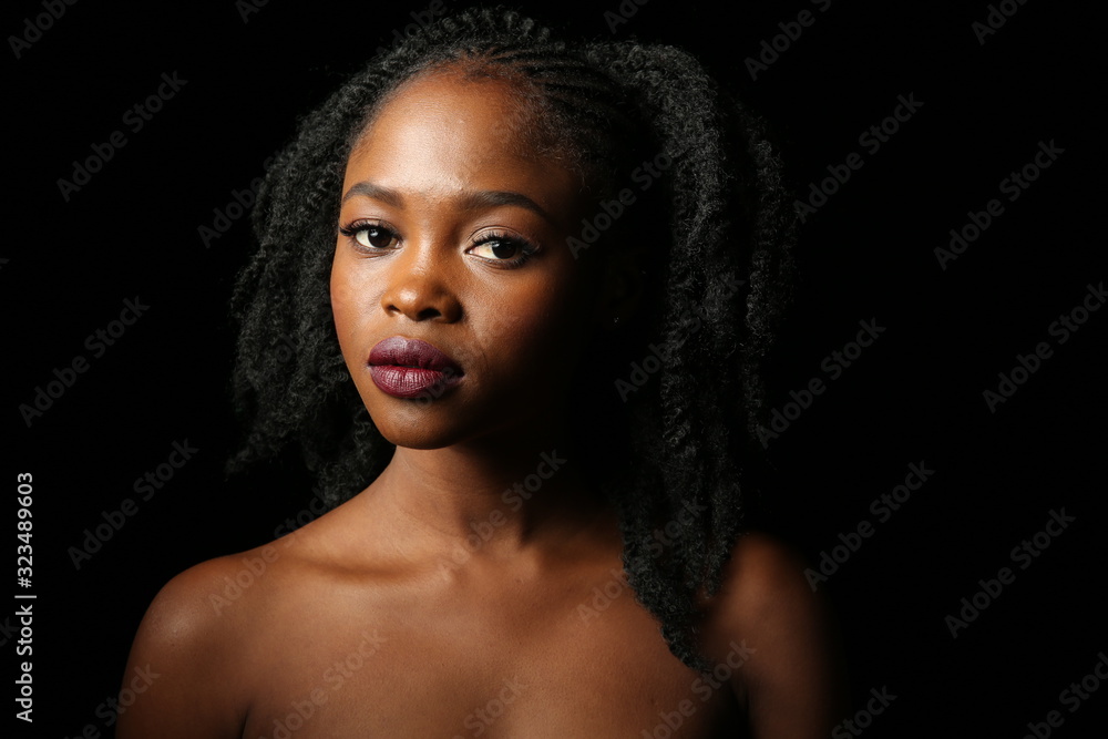 Portrait of a young beautiful African woman with thick black curly hair on an isolated black background Portrait of a young beautiful African woman with thick black curly hair on an isolated black background