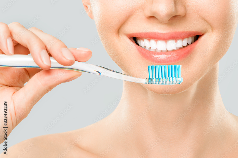 Beautiful smiling woman cleaning her teeth with a toothbrush in a dental hygiene concept. Isolated on white Beautiful smiling woman cleaning her teeth with a toothbrush in a dental hygiene concept. Isolated on white