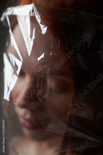Portrait of a young girl with a plastic bag on her head. The concept of plastic pollution of nature. Excess plastic in a person's life       photo