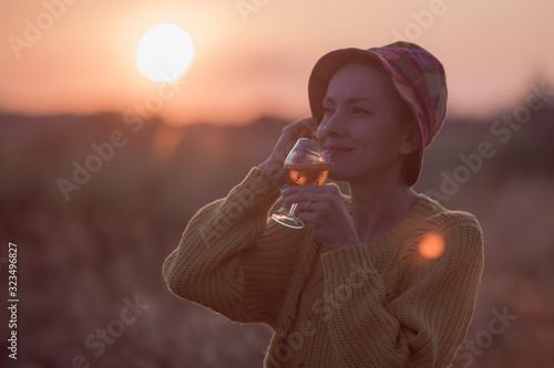 Woman with a cocktail over suset sky in orange colors