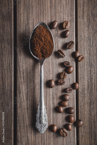 Coffee in a spoon surrounded by beans on a wooden background