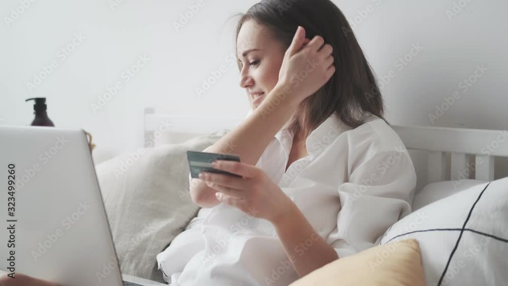 woman buys online at home. girl enters credit card number on laptop. shopaholic buys on the internet woman buys online at home. girl enters credit card number on laptop. shopaholic buys on the internet