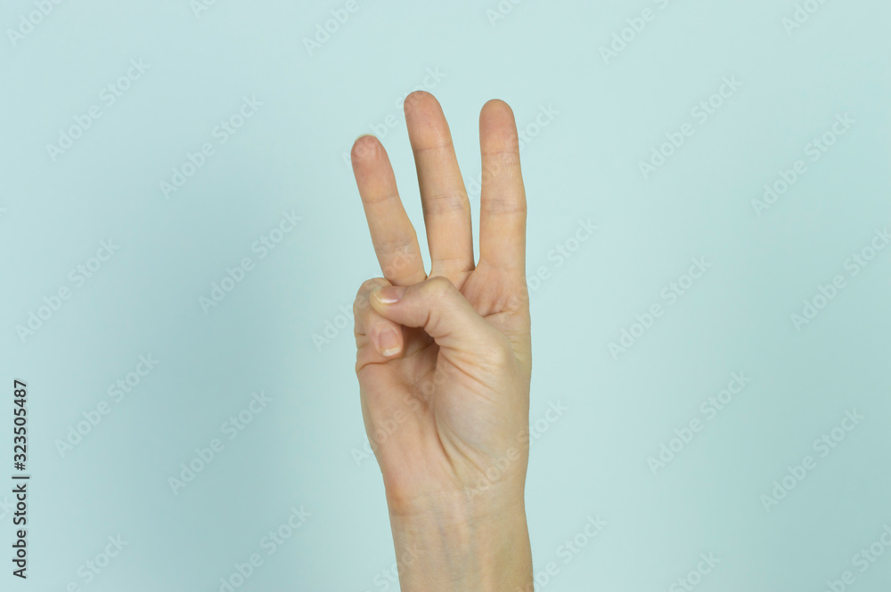 Three fingers displayed by a human hand isolated on a blue background.