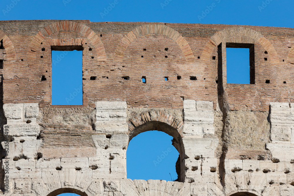 detail of the ancient Colosseum perimeter walls in Rome with blue sky