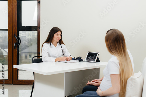 A young couple waiting for a baby to consult a gynecologist after an ultrasound. Pregnancy, and health care