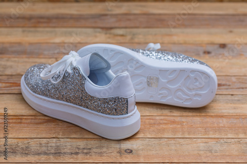 Glittery sneakers on wood background, close-up