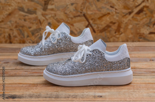 Glittery sneakers on wood background, close-up