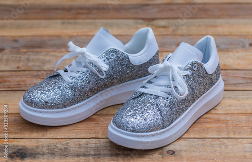 Glittery sneakers on wood background, close-up