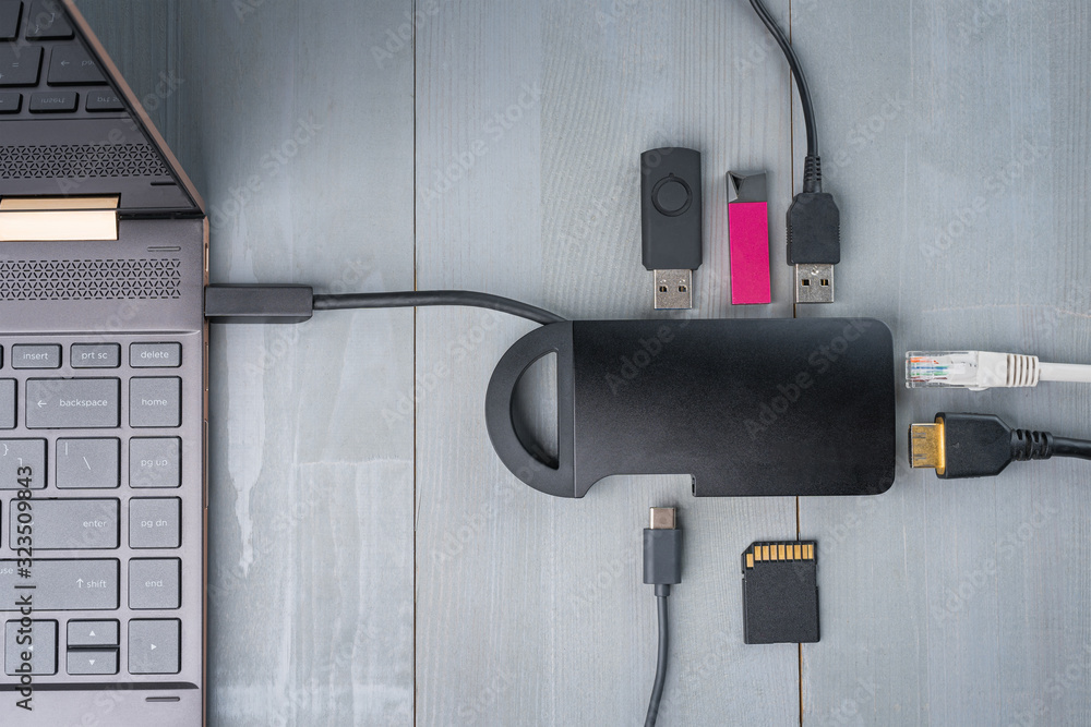 USB Type C adapter or hub connected to the laptop with various accessories - pendrives, hdmi, ethernet, memory card, cables. Flat lay top view.