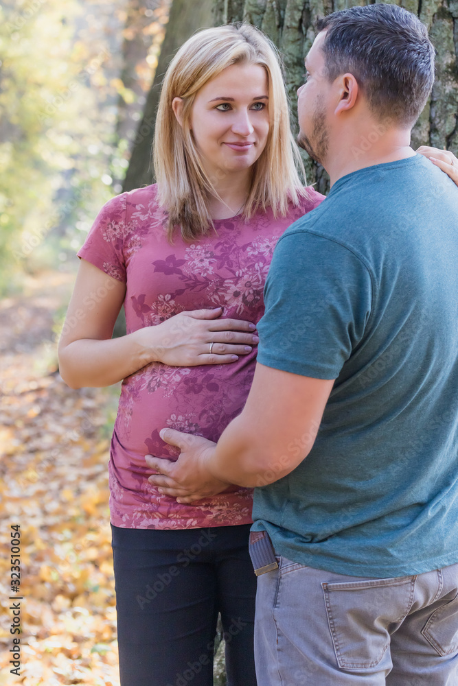 Young man and woman are expecting new baby. They both touch the belly of the expectant mother and are looking into their eyes. Vertically. Young man and woman are expecting new baby. They both touch the belly of the expectant mother and are looking into their eyes. Vertically.