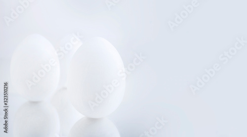 Chicken eggs painted white on a gray background are reflected on a mirror surface. Creative greeting card Happy Easter. Copy space