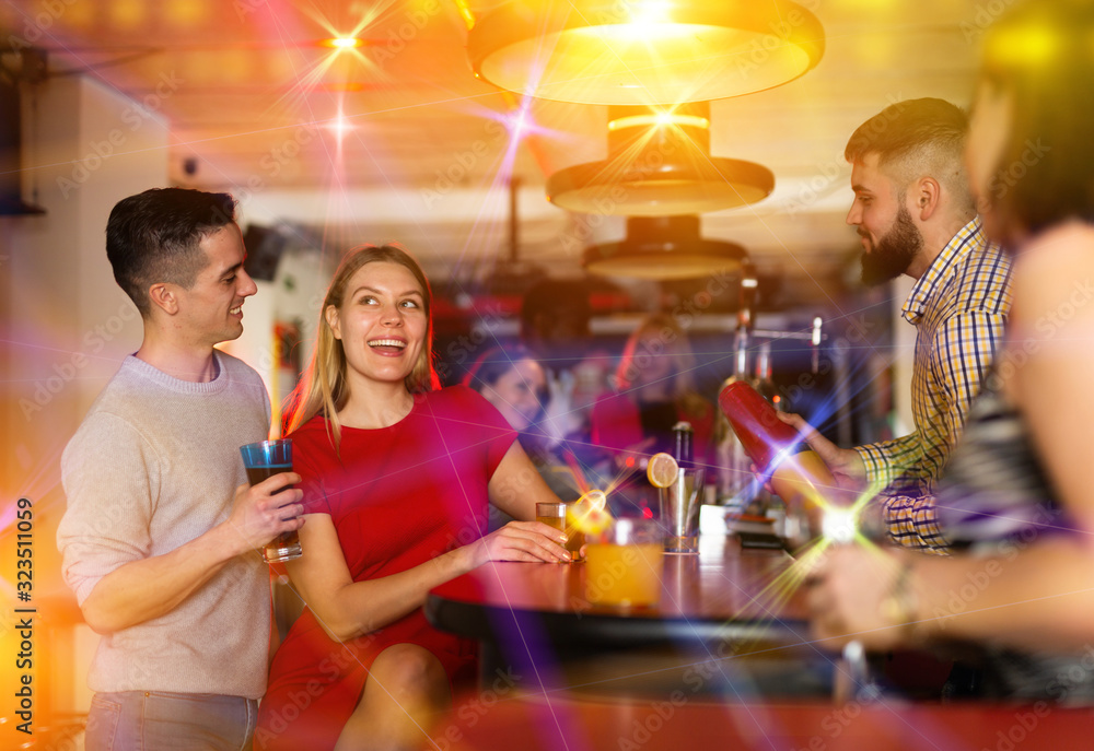 Bartender shaking cocktail for friends in nightclub