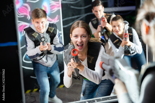 Portrait of excited woman holding laser gun in arena, playing laser tag game with friends